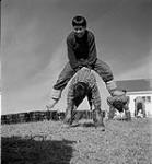 [Two boys playing leapfrog, Kinngait, Nunavut]. [between 1956-1960]