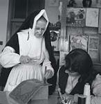 Religieuse enseignant à un élève comment travailler le cuir au couvent Notre-Dame, Sherbrooke, 1957. 1957