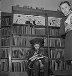 Children's Art Classes, Lismer's, two girls in front of book shelves. [between 1939-1951].