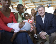 [Canadian Prime Minister Stephen Harper chats with women waiting to have their children vaccinated while visiting a hospital in the neighbourhood of Cité Soleil in Port-au-Prince, Haiti] 20 July 2007