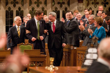 [Prime Minister Stephen Harper and Jack Layton, Leader of the Official Opposition, drag Andrew Scheer, the new Speaker of the House of Commons, to his chair in the House of Commons] 2 June 2011