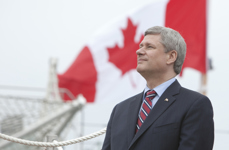 [Prime Minister Stephen Harper looks up and the HMCS St. John's following a fleet review of 28 Canadian and foreign warships at anchor in Bedford Basin and Halifax Harbor] 29 June 2010