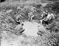 Canadian troops making good use of a shell hole before an attack on Fritz's trenches at night. June, 1917 June, 1917.