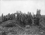 Canadian Pioneers carrying trench mats pass Boche prisoners and wounded. Battle of Passchendaele. November, 1917 November, 1917.