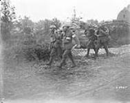 Canadians wearing gas masks bringing in wounded. Battle of Amiens. August, 1918 Aug. 1918