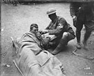 Wounded Canadian getting a drink from a stretcher bearer. Advance East of Arras. October, 1918 October 1918.