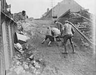 A Canadian helps two little French boys up the slope of a bridge destroyed by the enemy near Denain. November, 1918 November 1918.