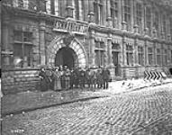 Canadians with French Gendarmes and civilians outside the Hotel de Ville, Valenciennes. November, 1918 Nov. 1918.