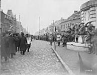 Denain veterans march past with a Canadian Brigade that captured Denain. Prince of Wales salutes the flag Oct. 1918