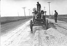 Low cost road construction in Saskatchewan. Blader spreading wind rowed gravel. 1930