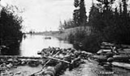 Indian fish trap on small stream flowing into L. Athabaska. Stream is dammed and a portion surround by rocks placed to prevent fish getting out
