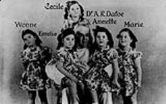 The Dionne Quintuplets, Yvonne, Emelie, Cecile, Annette and Marie, with Dr. Allan Roy Dafoe who delivered them ca. 1940