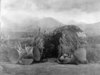 A Mono home. The Mono, [a Sheshonean division] inhabited east-central California from Owens Lake to thehead of the southerly affluents of Walker River. This [wickiup] dwelling is a typical winter shelter. Burden baskets and sieves are in the foreground 1926