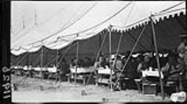 Men at dinner in a tent, in Niagara Camp, when the C.O.T.C. [Canadian Officers Training Corps], McGill and Varsity men were there 11 May 1915
