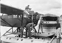 Fairchild Wasp used in Trans-Canada flight showing S/L Godfrey inspecting motor 18 Aug. 1928