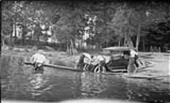 Men prying automobile out of Moon River, [Ont.], with a pole 17 Aug., 1917