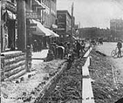 Mr. D. Brennan and crew opening trench for cable of Bell Telephone Company, Main Street, Winnipeg, Man., 1903 1903