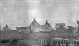 [Teepees and canoes at Chisasibi] Original title: Indian camps, H.B. Co. in distance July 1927.