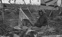 Elderly Gwichya Gwich'in woman cleaning hide 1921