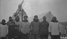 [Group of Inuvialuit men and boys in front of a tent and a teepee]. Original title: Group of Eskimos near Kittigazuit 1925