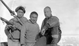 [L. to R.: Inuuk Sadluk and Kaingak, with Constable Stanley Wilson of the Dundas Harbour Detachment, Royal Canadian Mounted Police (R.C.M.P.) on board the "Beothic"] Original title: L. to R.: Eskimos Sadluk and Kaingak, with Constable Stanley Wilson of the Dundas Harbour Detachment, Royal Canadian Mounted Police (R.C.M.P.) on board the "Beothic" August 1928.