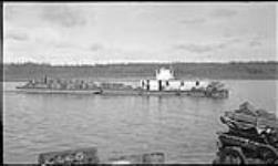 N.T. Co. paddle wheeler "Silver Queen" and barge loaded with empty barrels for oil wells from foot of rapids roads 1937