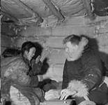 An unidentified Inuit woman talking to Cst. W.L. Carey inside an igloo at Windy River 10 December 1950.