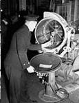 A Chief Electrical Artificer examining a searchlight in the Electrical Artificers' Workshop, H.M.C. Dockyard, Halifax, Nova Scotia, Canada, 18 November 1942 November 18, 1942.