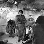 Inuit actors inside National Film Board igloo studio at Chesterfield Inlet, N.W.T., with movie lights on wall n.d.