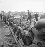 Personnel of the 3rd Battalion, Royal Canadian Engineers (R.C.E.) lowering a section of the Ostend-Ghent oil pipeline into a trench, Ostend, Belgium, 18 October 1944 October 18, 1944.