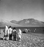 Eskimos watch landing of helicopter from C.G.S. "C.D. Howe", Eastern Arctic Patrol Vessel, at Arctic Bay, N.W.T. [July 1951] July 1951.