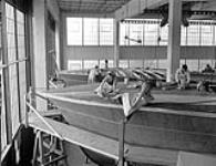 Workers covering the hulls of motor torpedo boats under construction at Canadian Power Boat Company with linen fabric, Montreal, Québec, Canada, 24 April 1941 Apri1 24, 1941.