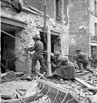 Infantrymen of The Regina Rifle Regiment and a despatch rider firing into a damaged building, Caen, France, 10 July 1944 July 10, 1944.