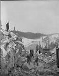 Travailleurs poursuivant le forage du roc malgré une tempête de neige pendant la construction du chemin de fer Quebec North Shore & Labrador automne 1951