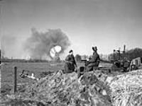 Gunners of the 4th Light Anti-Aircraft Regiment, Royal Canadian Artillery (R.C.A.), observing a burning German ammunition dump, Zutphen, Netherlands, 7 April 1945 April 7, 1945.