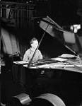 Pianist Allan Carmichael of No.11 Detachment of the Canadian Army Show during a recording session at Station BLA3, Oldenburg, Germany, 12 June 1945 June 12, 1945.