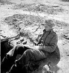 Captain E.N. Frost of The North Nova Scotia Highlanders, whose hand grenades are ready for use as he writes a letter home from his slit trench in Normandy, France, 22 June 1944 June 22, 1944.