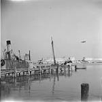 Observation Post Aircraft flying over blasted quay. Ortona, Italy, Feb. 1944 FEB. 1944