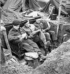 Troopers of The Fort Garry Horse reading mail on a couch in their slit trench in the Hochwald, Germany, 5 March 1945 March 5, 1945.