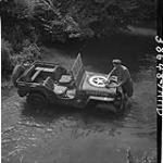 Bombardier Bob Stuchbury washing jeep in creek en route to Falaise. Le Beffen, France, 13 Aug 1944 13 AUG 1944