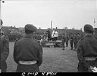 Easter Church Parade Service at 1st Canadian Corps Headquarters. On the platform are Lt.-Col. J. Logan-Veneta giving sermon, H/Capt, W.G. Brood and H/Capt. J.R. McMahon, H/Major J.A. Falconbridge is standing at back of platform Apr. 1945