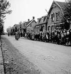Des enfants néerlandais portant le bonnet orange traditionnel envoient la main aux soldats de la 2e Division d'infanterie canadienne qui traversent Beveland pendant son occupation. Kabbendijke, Pays