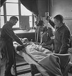 Captain Earl Bourbonnais giving plasma to casualty, assisted by Sergeant T.F. McFeat and Private J. Viner, 9 C.I.B., 23 Field Ambulance, Basly, France, 27 June 1944 27 JUNE 1944