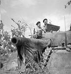 Lieutenant R.O. Campbell (left) of the Canadian Army Film and Photo Unit and Corporal H.H. Mowbray with a movie camera mounted on the turret of a Sherman tank near the Hitler Line, Italy, 23 May 1944 May 23, 1944.