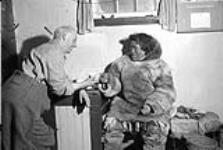 George Lush having tea with an Inuit man inside his shack 1949-1950.