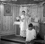 Father Joseph Buliard saying mass assisted by Inuit altar boy, Kelora, Oblate fathers' Mission Mar. 1946.