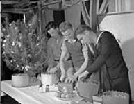 Leading Seaman Pat Hughes and Able Seamen Fred Derkach and Orville Campbell distributing nuts and oranges during preparations for Christmas dinner aboard the infantry landing ship H.M.C.S. PRINCE DAVID, Ferryville, Tunisia, 25 December 1944 Deember 25, 1944.