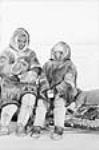 [Inuit couple, Joe Ulurksit and his wife Gemma in caribou parkas sitting on a komatik, Kugluktuk] 1949.