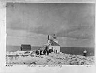 Lighthouse tower and dwelling with group of unidentified men 1890