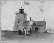 Lighthouse and attached dwelling with a family group in foreground 1890